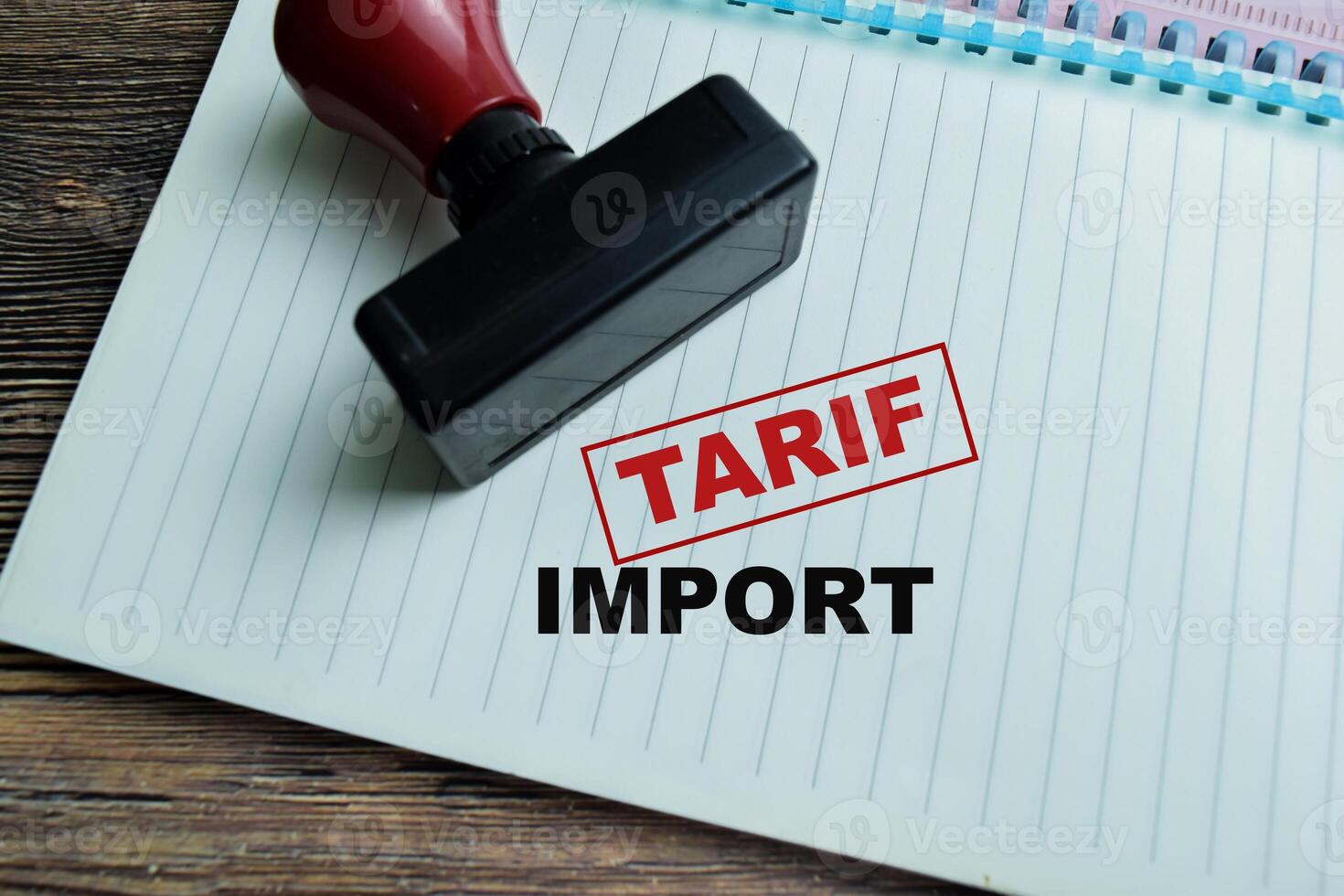 Red Handle Rubber Stamper and Tarif Import text above book isolated on wooden background photo