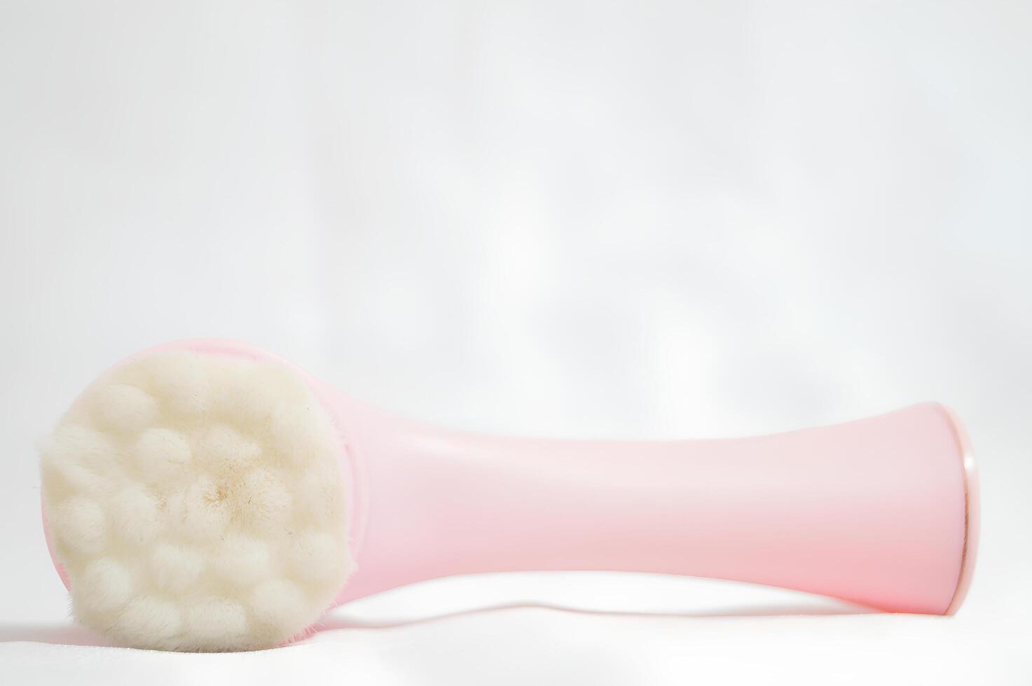 A pink brush with white bristles is laying on a white surface photo