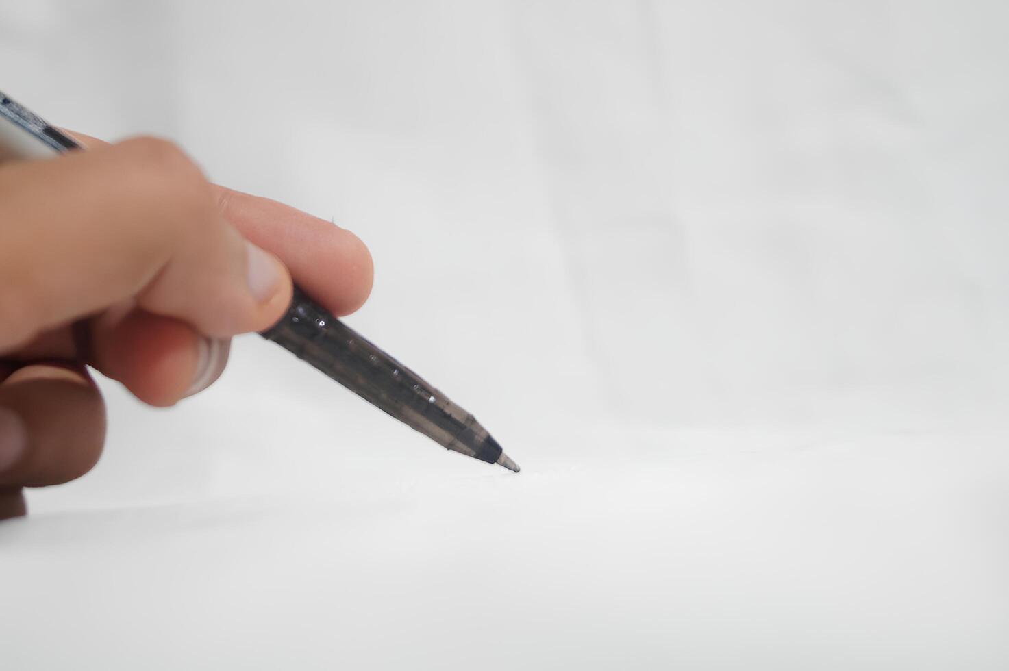 A person is writing with a pen on a white background photo