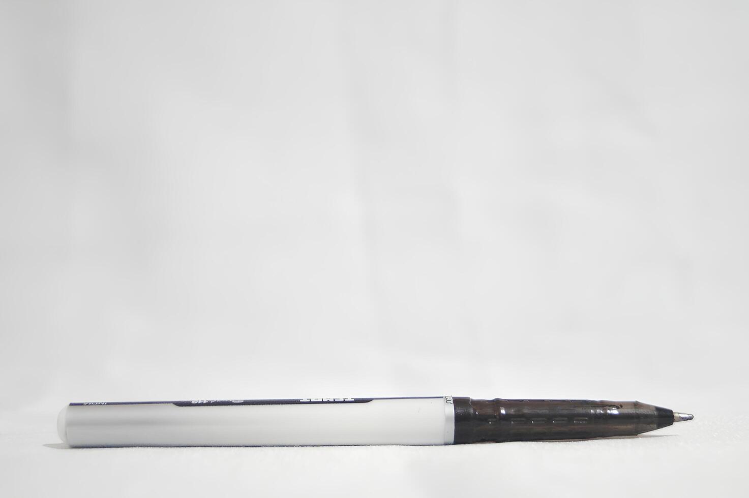 A black pen with a white tip sits on a white surface photo