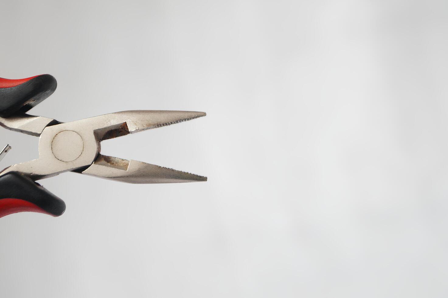 A pair of pliers with a red handle and a black tip photo