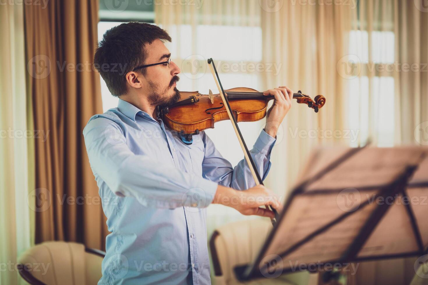 Man playing violin at home. He is practicing for live performance. photo