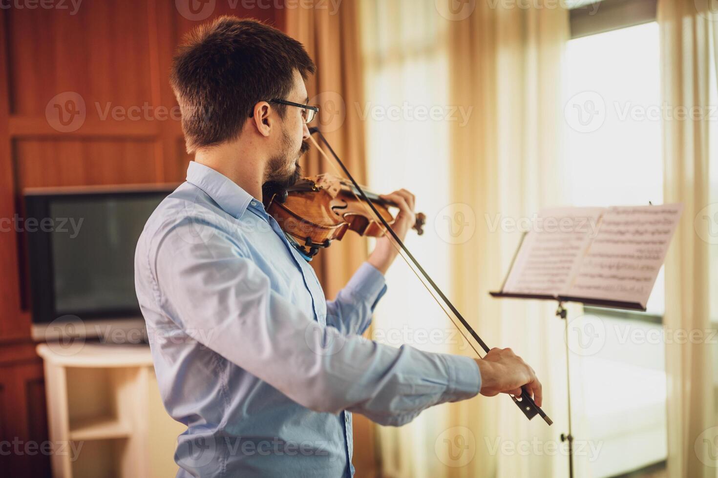 Man playing violin at home. He is practicing for live performance. photo