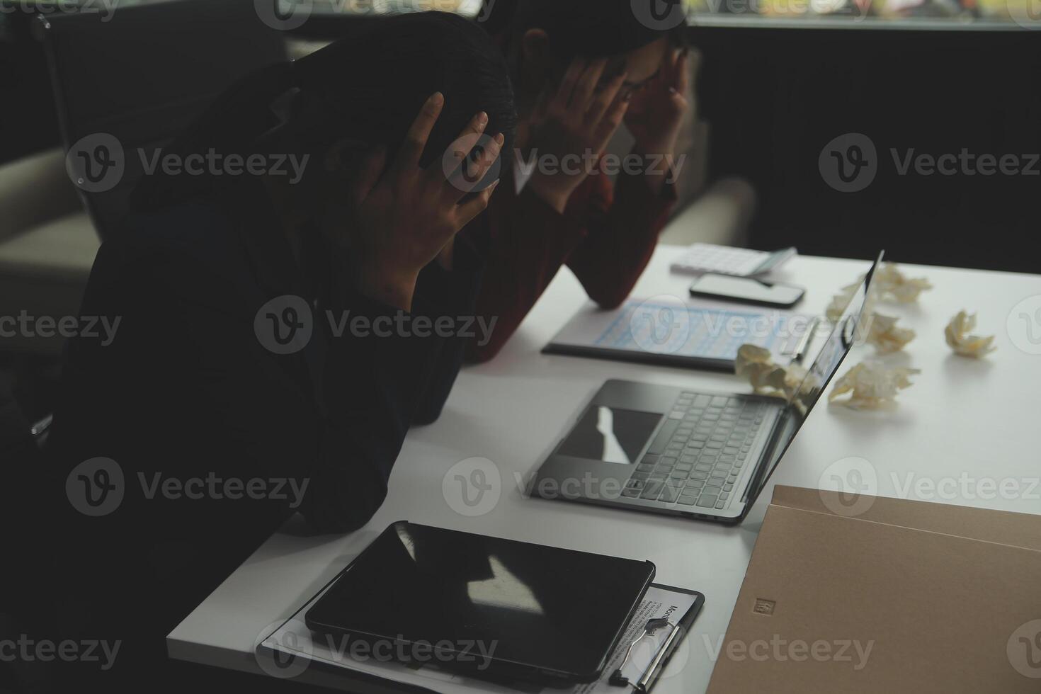 Stressed annoyed office employee manager having headache migraine at business meeting with his colleagues about business problem they have to solve. Stress at work or migraine concept. photo