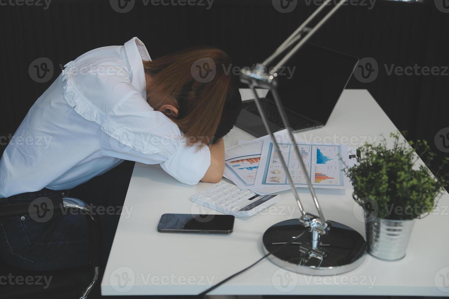 Businesswoman yawning while working with a laptop computer in the office, a woman in casual office lifestyle concept. photo