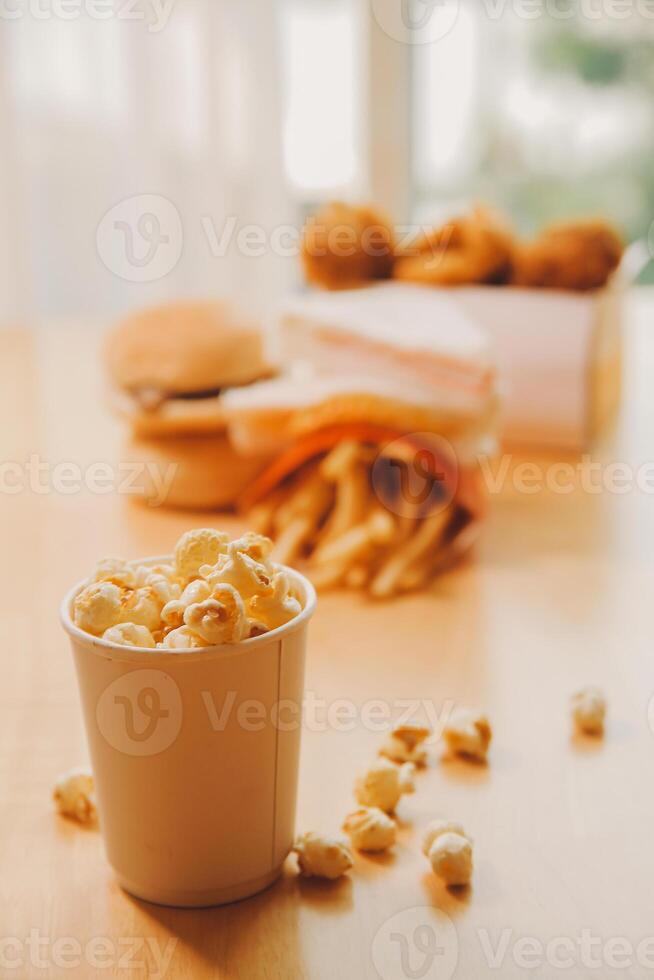 A bucket of popcorn, top-view, warm colors, light brown wooden background, flat lay, daylight macro close-up photo