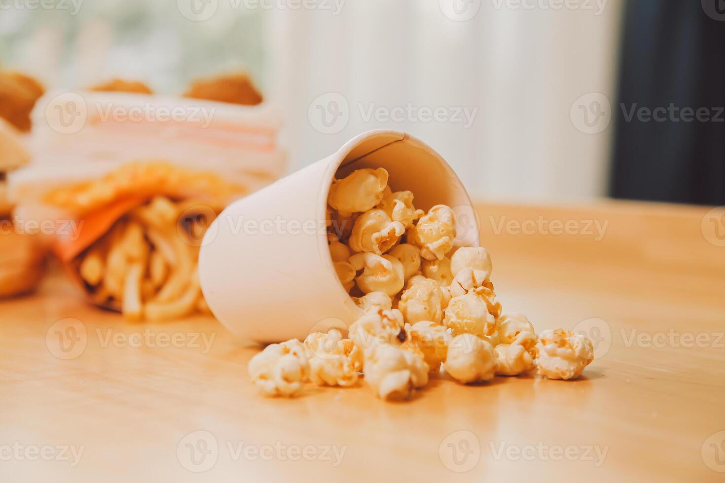 A bucket of popcorn, top-view, warm colors, light brown wooden background, flat lay, daylight macro close-up photo