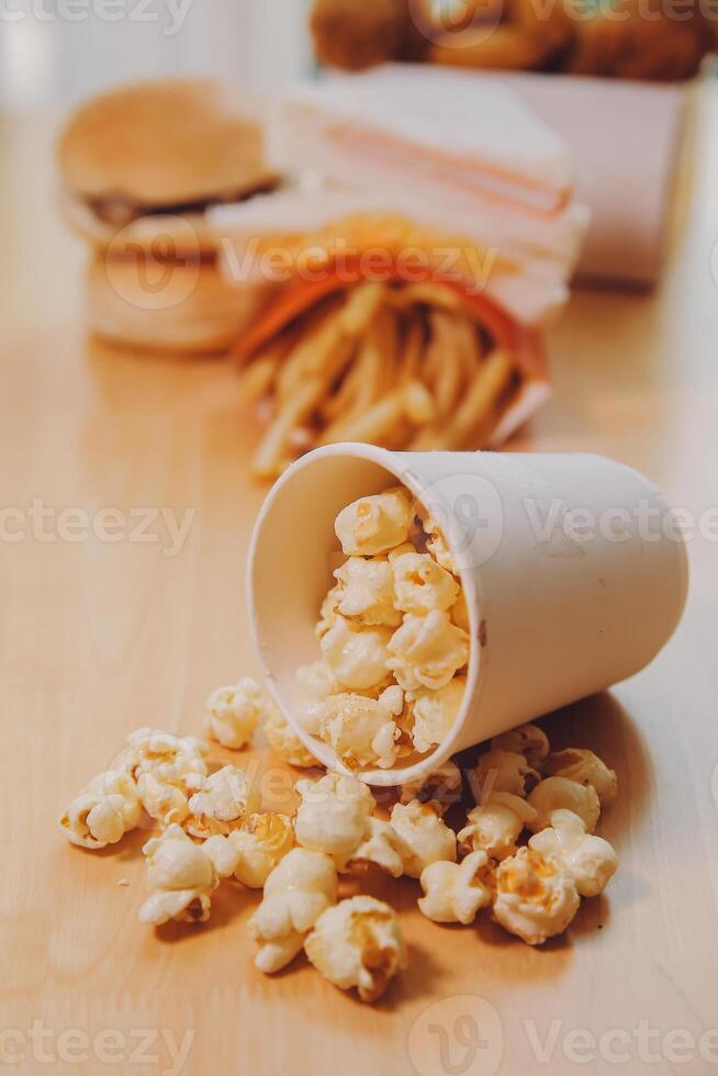 A bucket of popcorn, top-view, warm colors, light brown wooden background, flat lay, daylight macro close-up photo