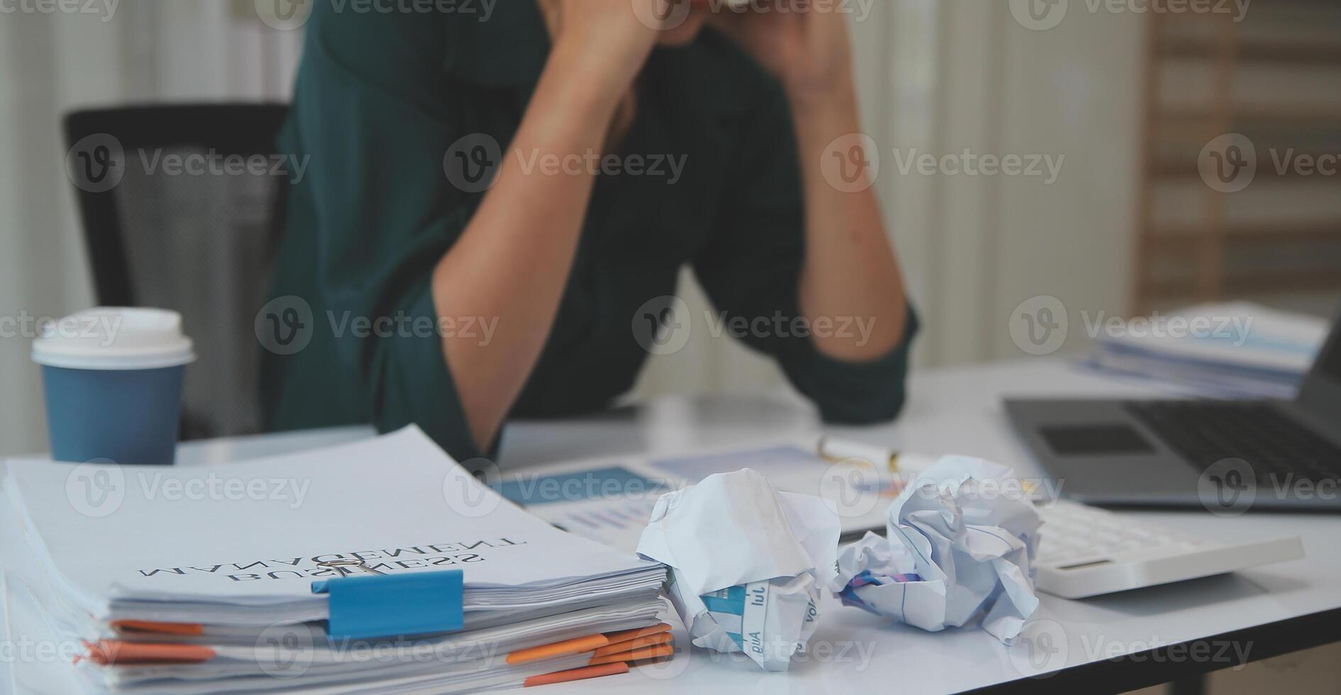 Asian women sitting in a home office With stress and eye strain.Tired businesswoman holding eyeglasses and massaging nose bridge. There are tablets, laptops, and coffee. photo