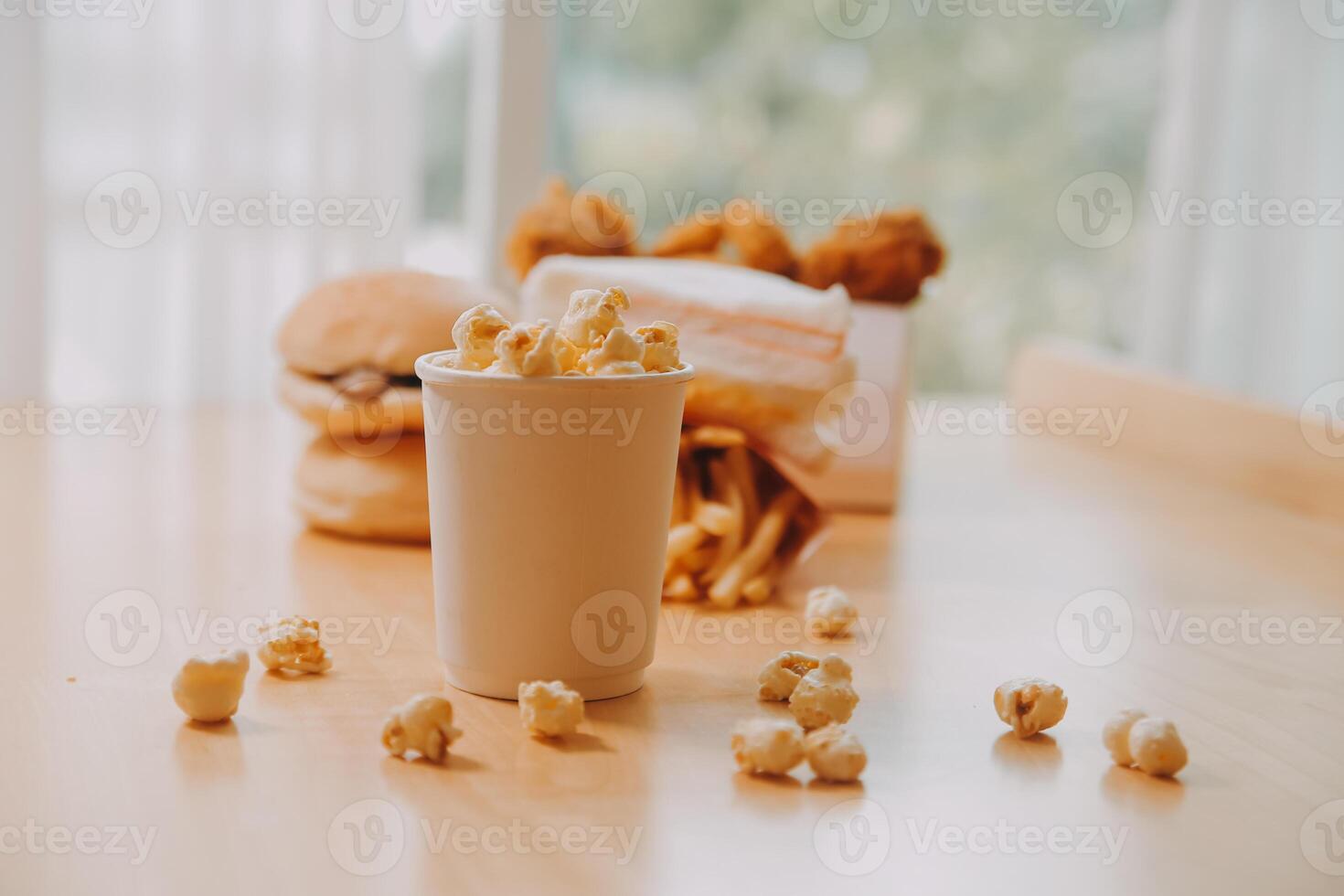 A bucket of popcorn, top-view, warm colors, light brown wooden background, flat lay, daylight macro close-up photo