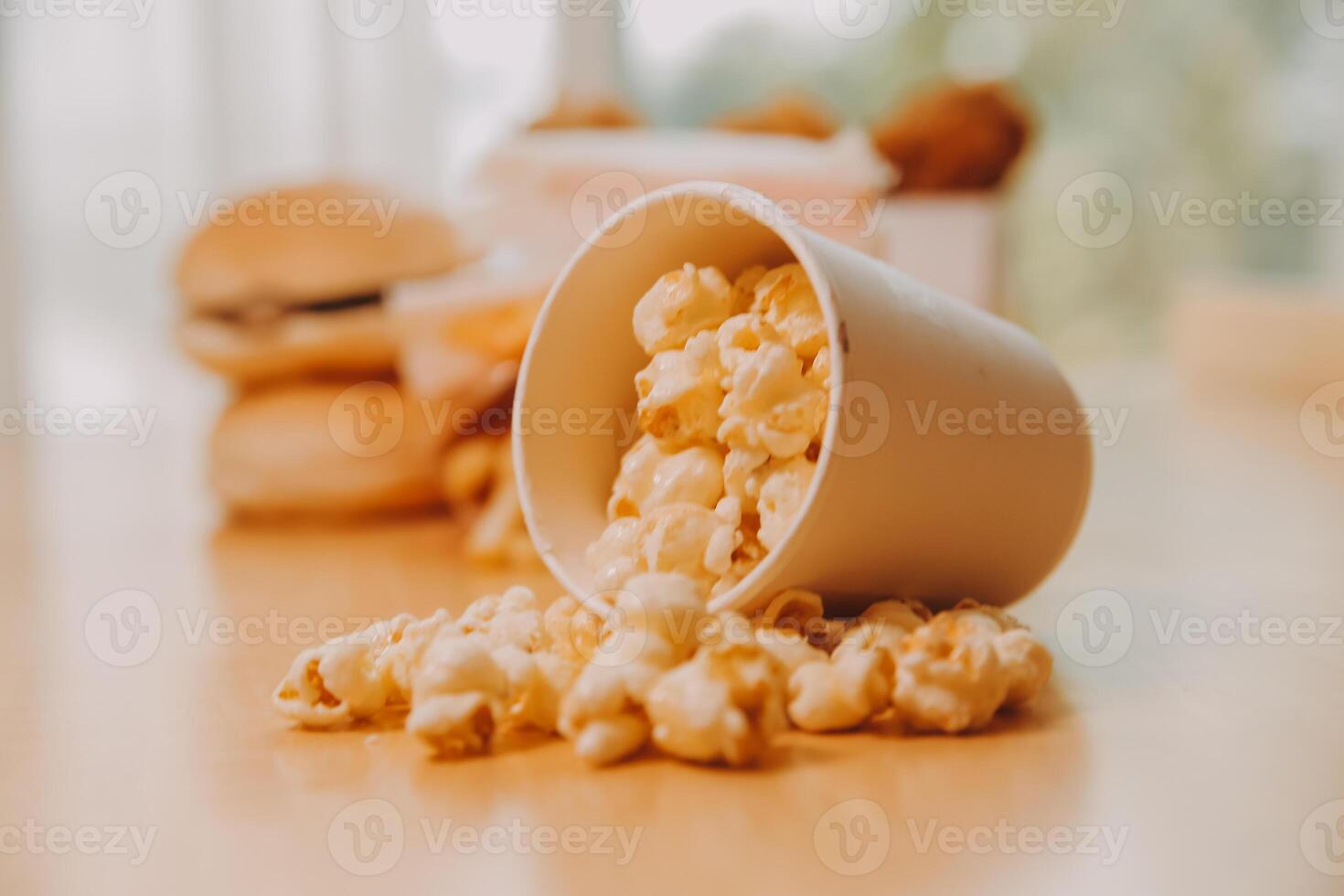 A bucket of popcorn, top-view, warm colors, light brown wooden background, flat lay, daylight macro close-up photo