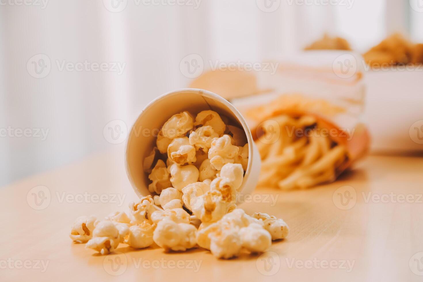 A bucket of popcorn, top-view, warm colors, light brown wooden background, flat lay, daylight macro close-up photo