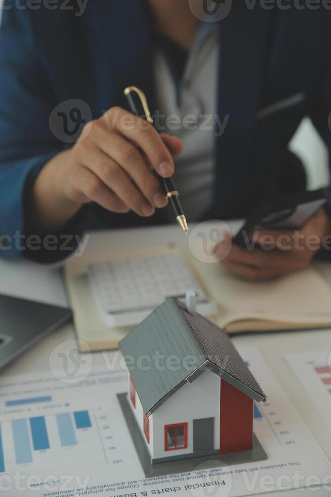 Businessmen holding pens, signing home titles with insurance, care about real estate services and the idea of real estate agents offering interest in installments to their customers. photo