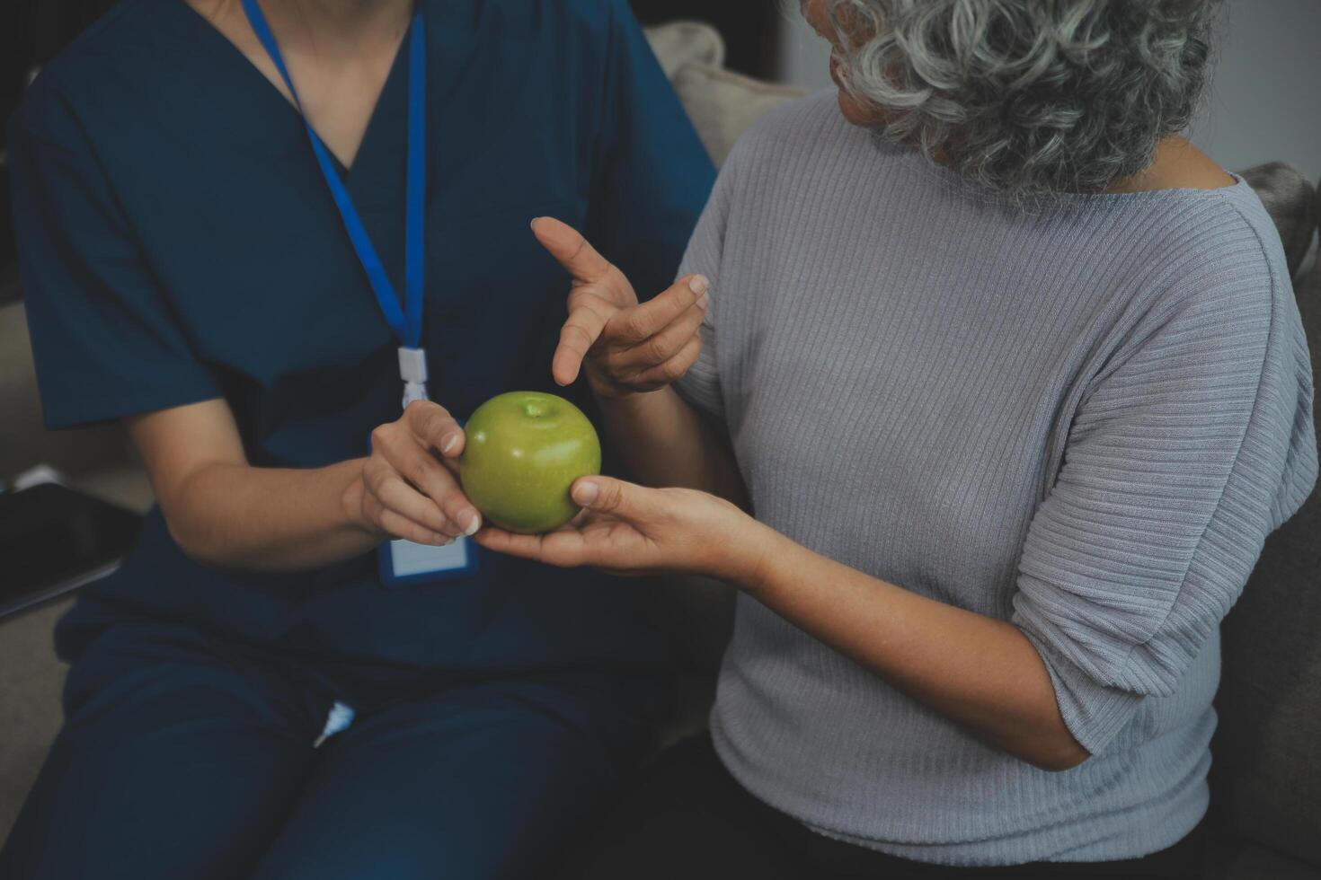 Happy young female nurse provide care medical service help support smiling old grandma at homecare medical visit, lady carer doctor give empathy encourage retired patient sit on sofa at home hospital photo