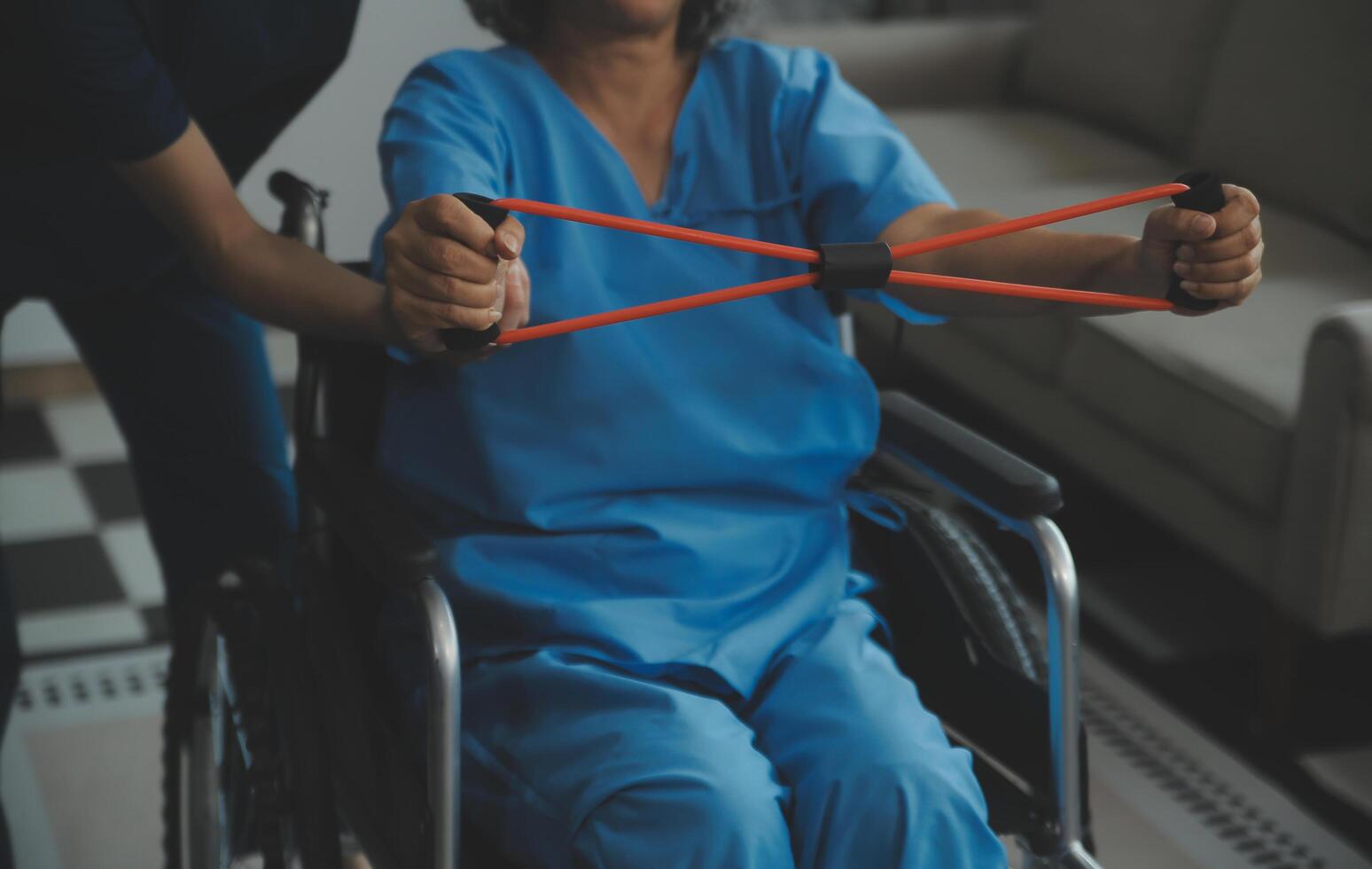 Personal trainer assisting senior woman with resistance band. Rehabilitation physiotherapy worker helping old patient at nursing home. Old woman with stretch band being coached by physiotherapist. photo