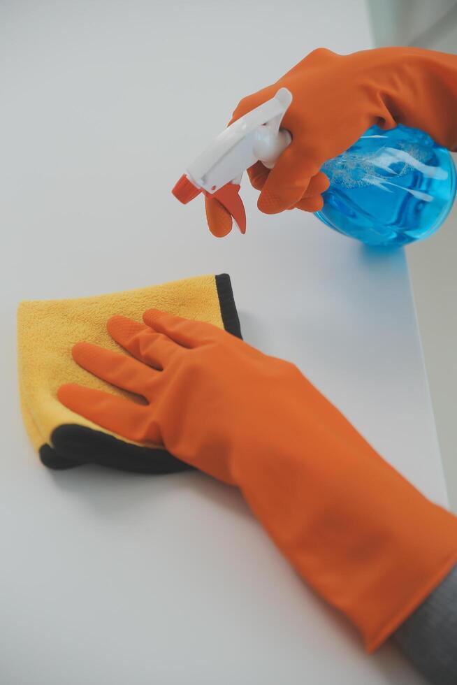 Woman cleaning table using rag and diffuser at home. photo