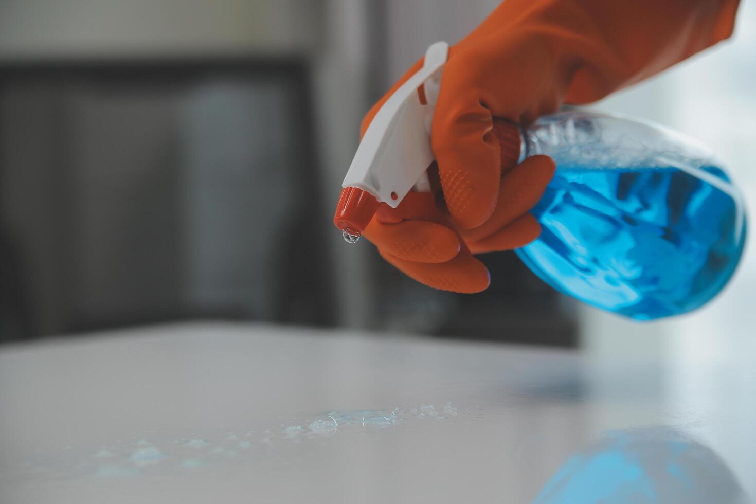 Woman cleaning table using rag and diffuser at home. photo
