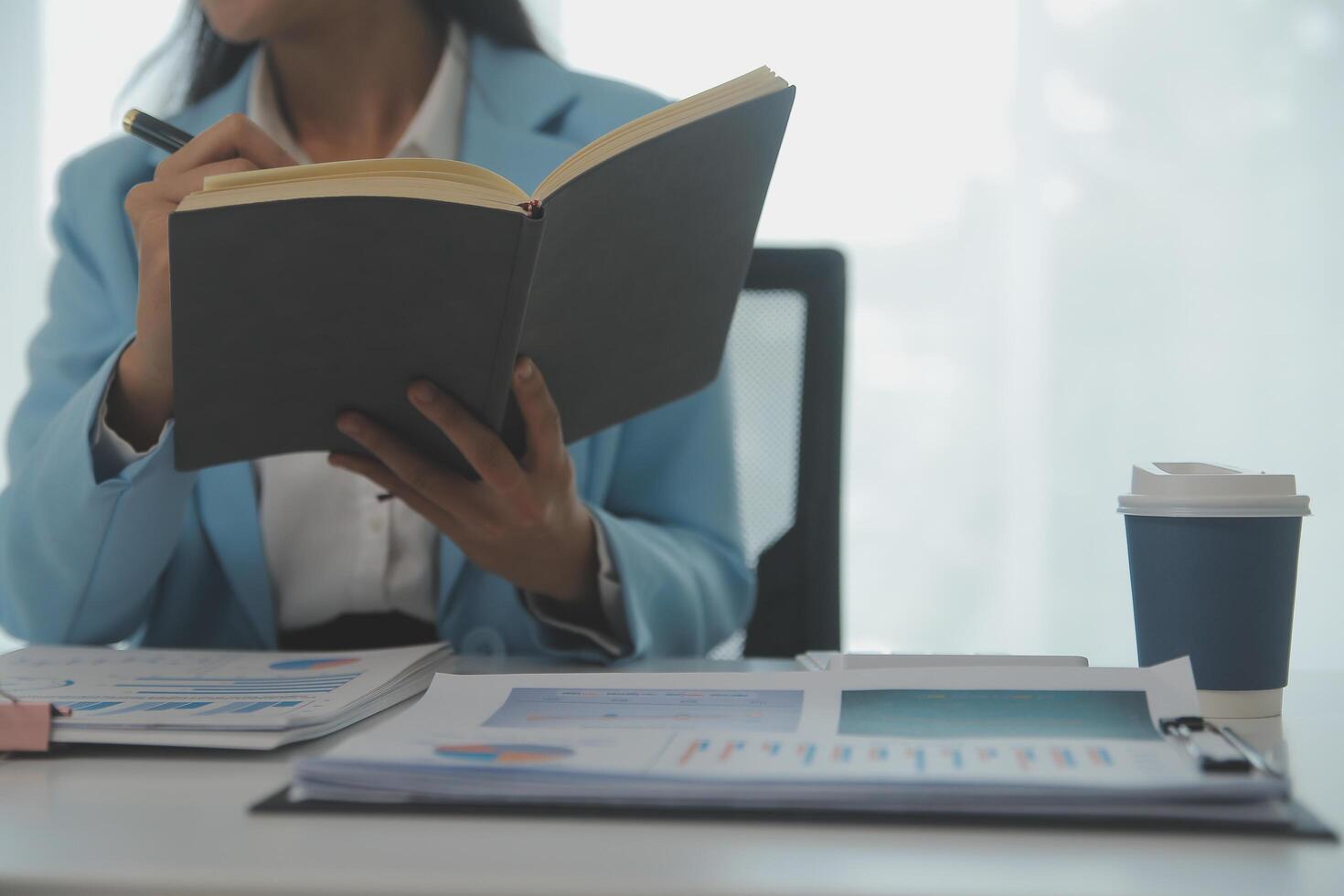 Charming Young asian businesswoman sitting on laptop computer in the office, making report calculating balance Internal Revenue Service checking document. photo