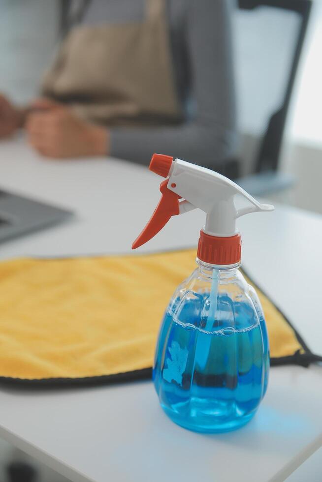 Woman cleaning table using rag and diffuser at home. photo
