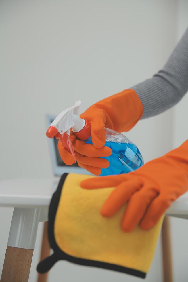 Woman cleaning table using rag and diffuser at home. photo