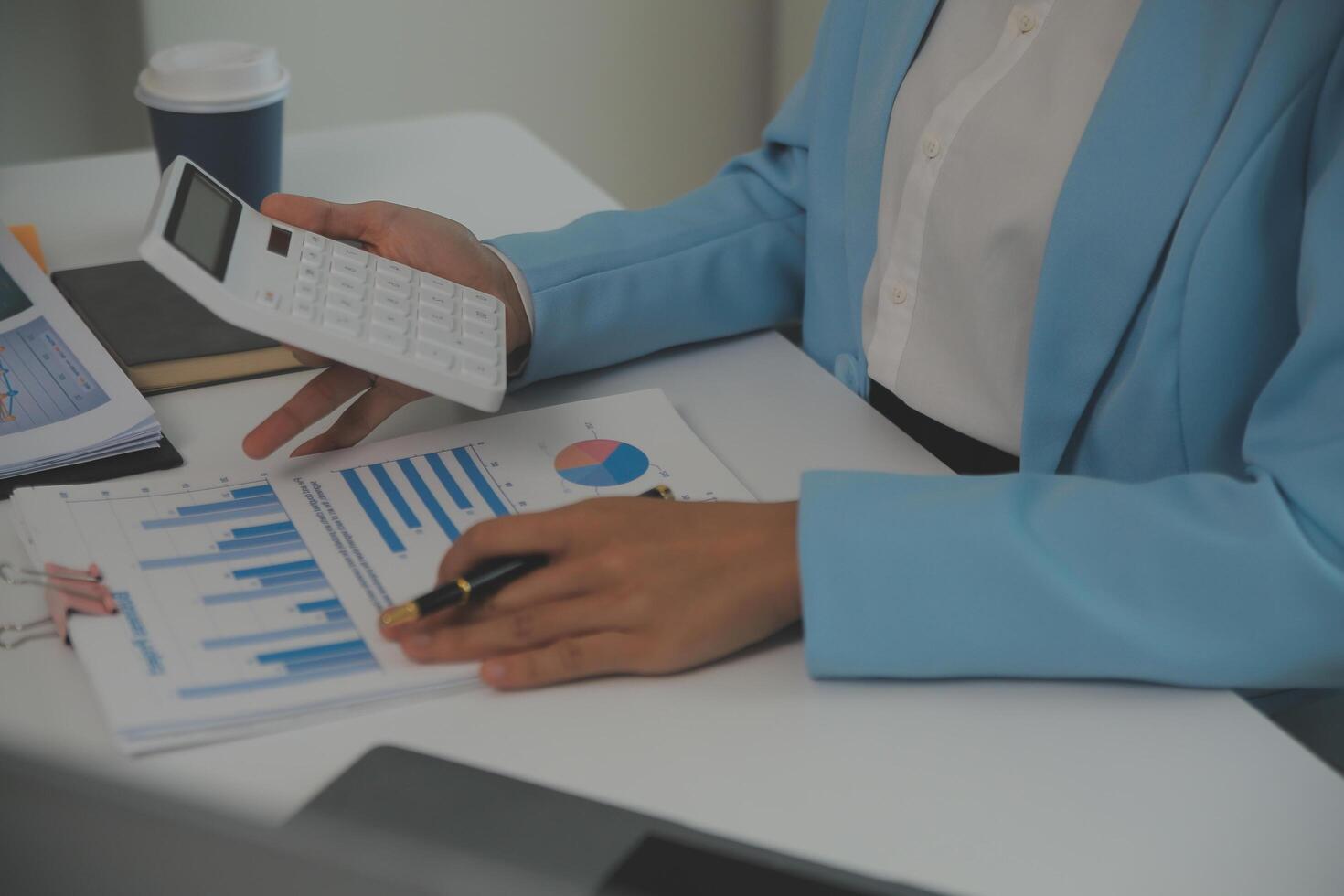 Charming Young asian businesswoman sitting on laptop computer in the office, making report calculating balance Internal Revenue Service checking document. photo