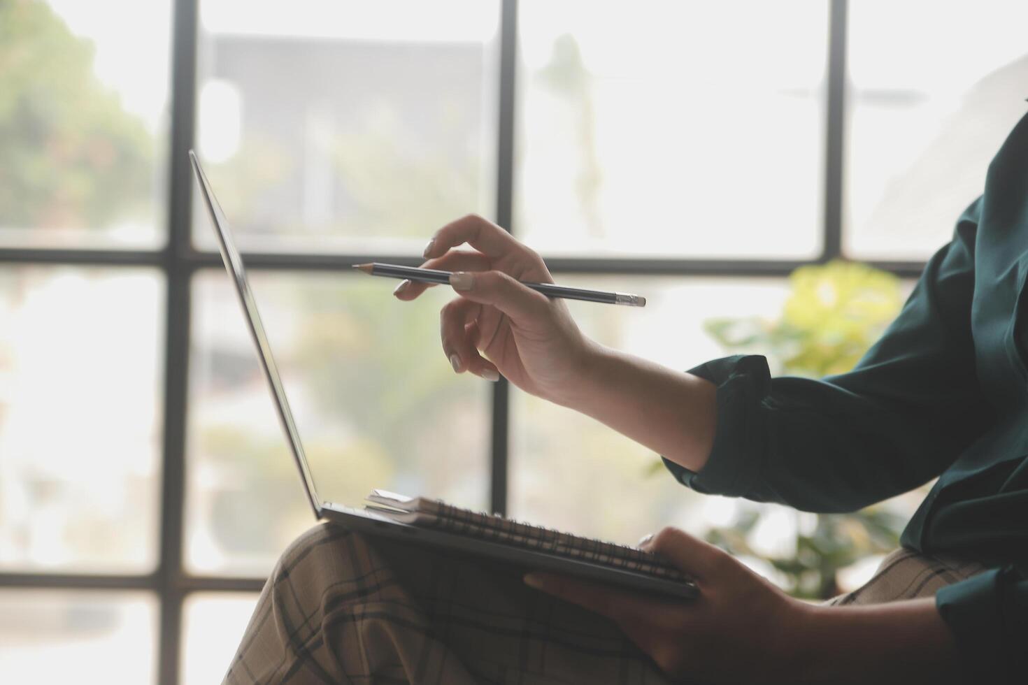 Distracted from work worried young woman sitting on couch with laptop, thinking of problems. Pensive unmotivated lady looking at window, feeling lack of energy, doing remote freelance tasks at home. photo