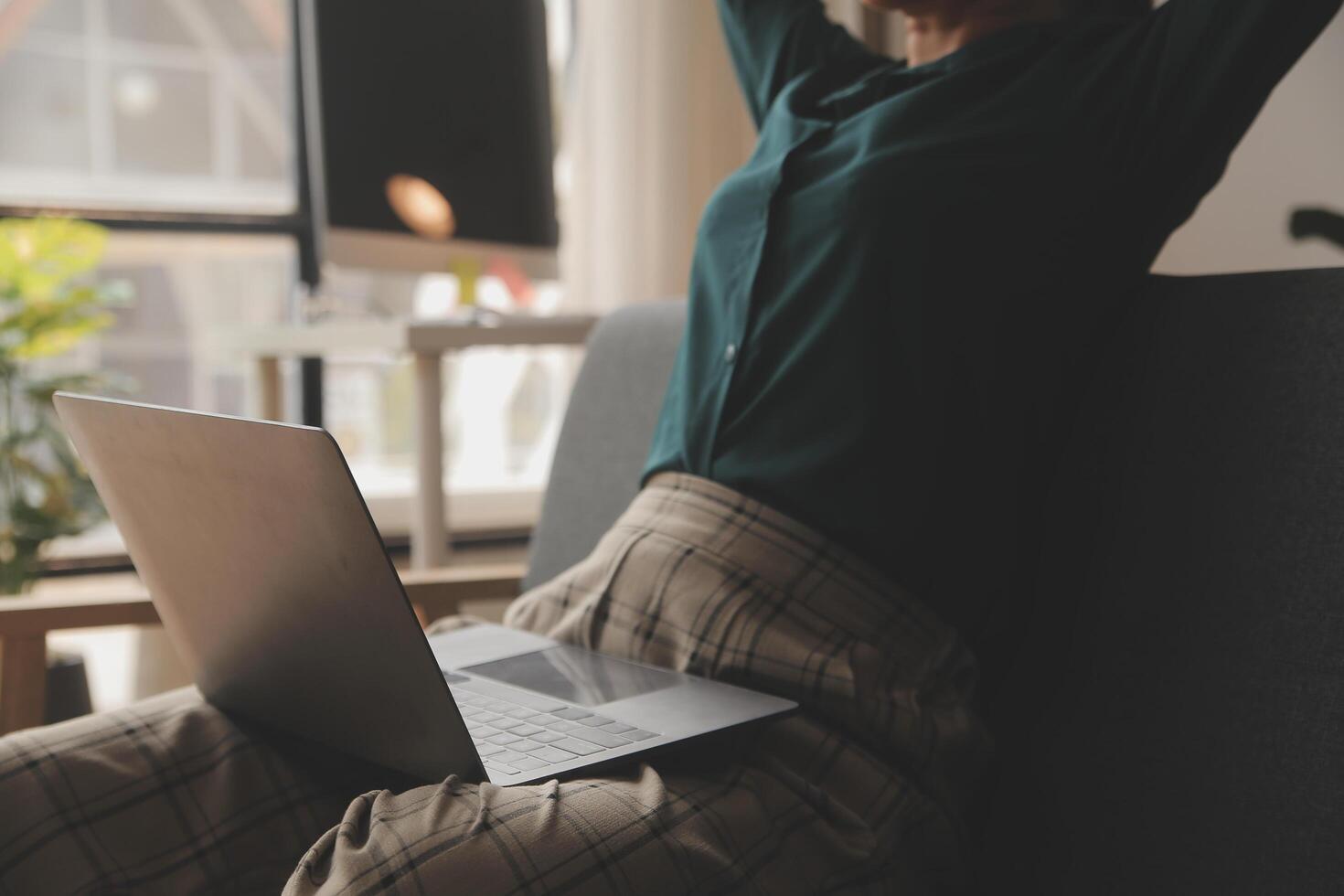 Distracted from work worried young woman sitting on couch with laptop, thinking of problems. Pensive unmotivated lady looking at window, feeling lack of energy, doing remote freelance tasks at home. photo