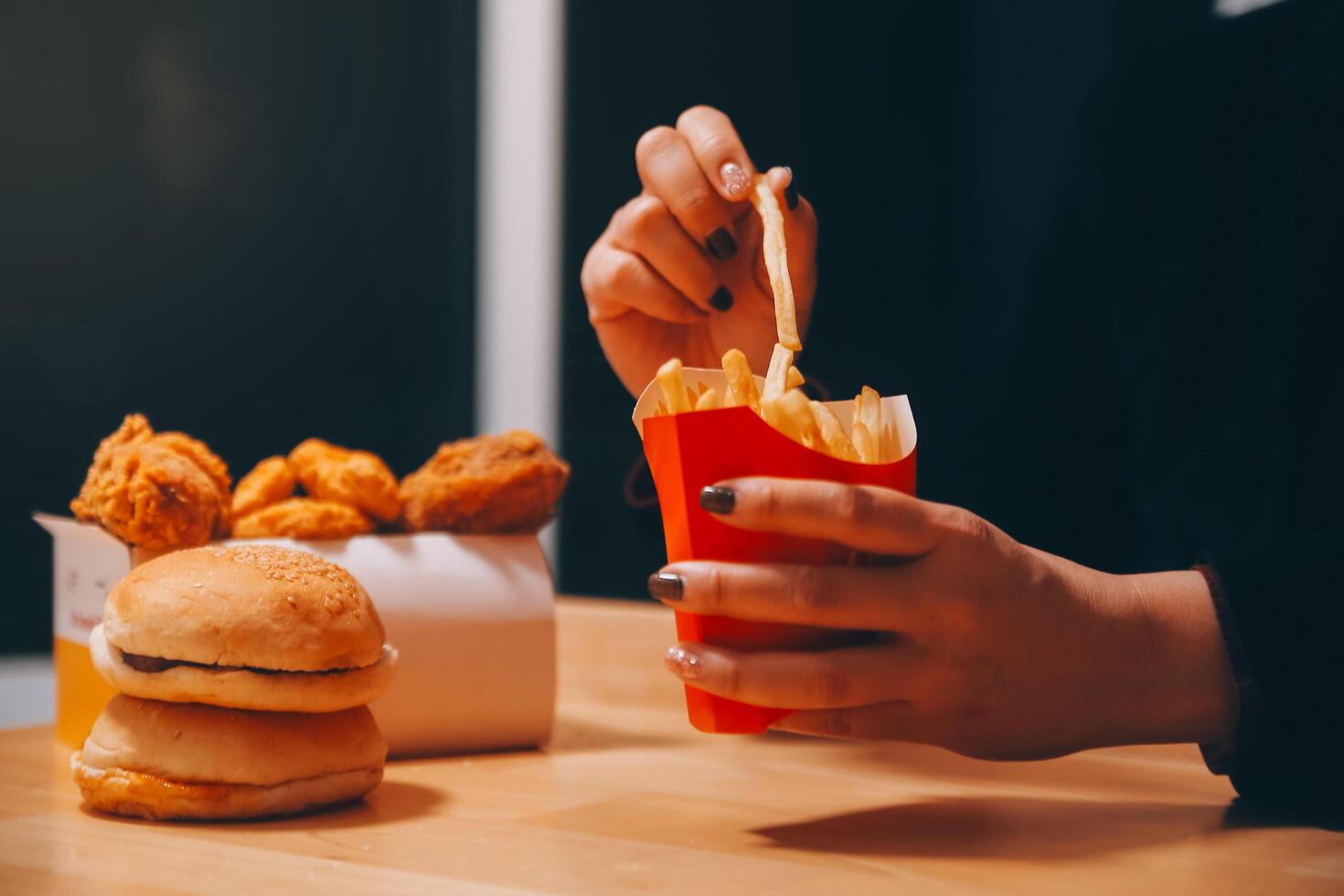 Asian woman holding french fries and eating happily in restaurant photo