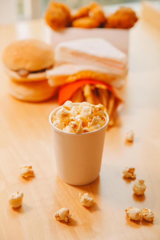 A bucket of popcorn, top-view, warm colors, light brown wooden background, flat lay, daylight macro close-up photo