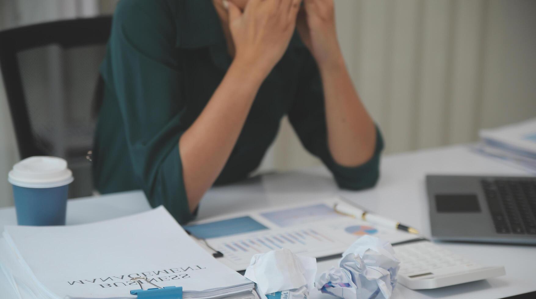 Asian women sitting in a home office With stress and eye strain.Tired businesswoman holding eyeglasses and massaging nose bridge. There are tablets, laptops, and coffee. photo