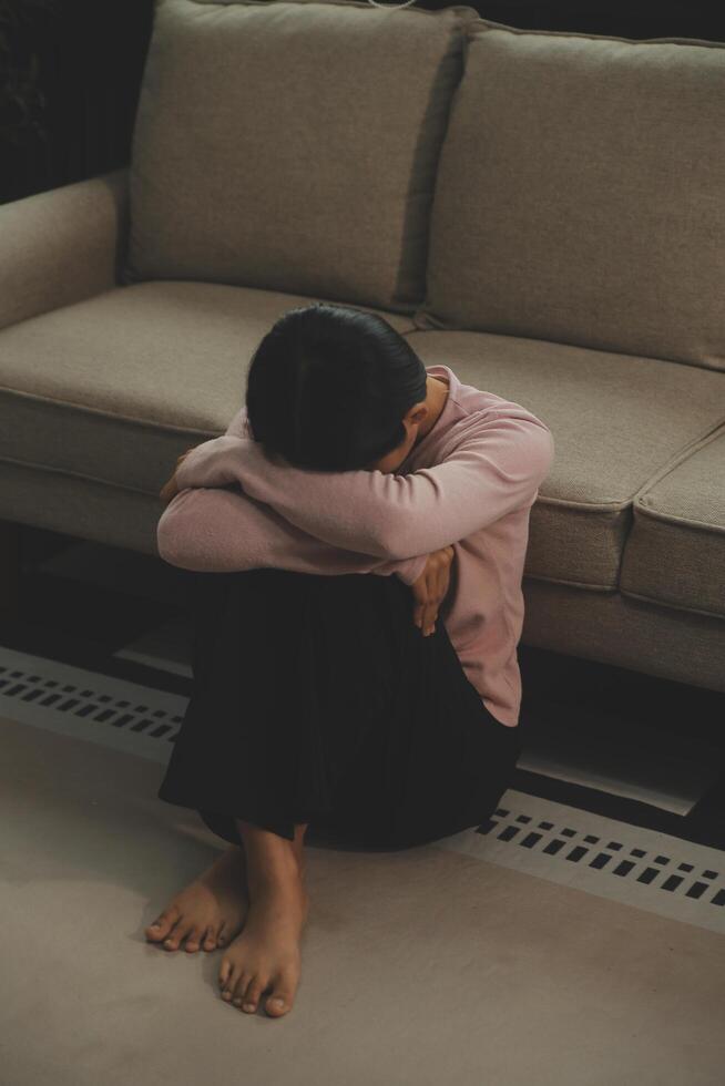Depressed woman sitting alone on the bed with hands on head feel stress, sad and worried in the dark bedroom and low light environment photo