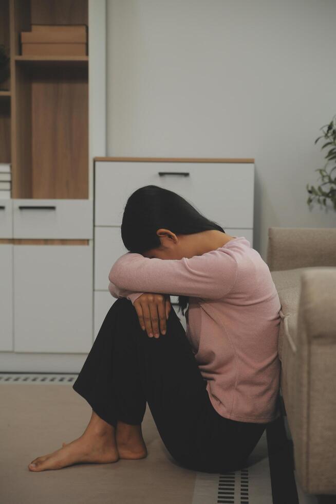 Depressed woman sitting alone on the bed with hands on head feel stress, sad and worried in the dark bedroom and low light environment photo