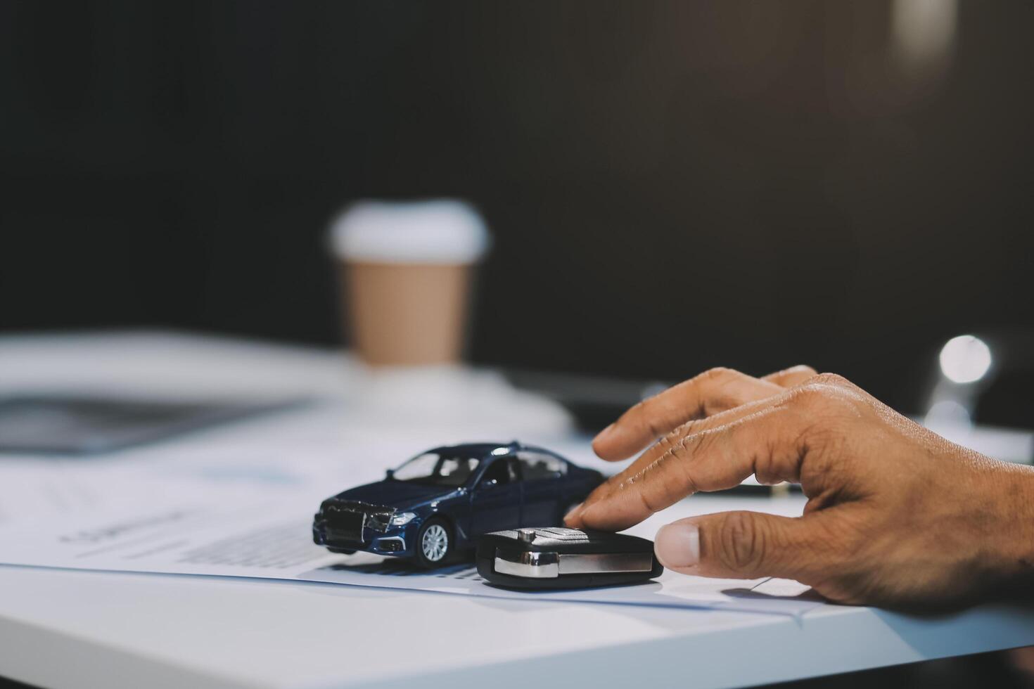 Car sales representative gives keys to new car owner, concept for car rental Focus on the key. Pick up the key. Close-up of the key transfer from the new machine to the buyer. photo