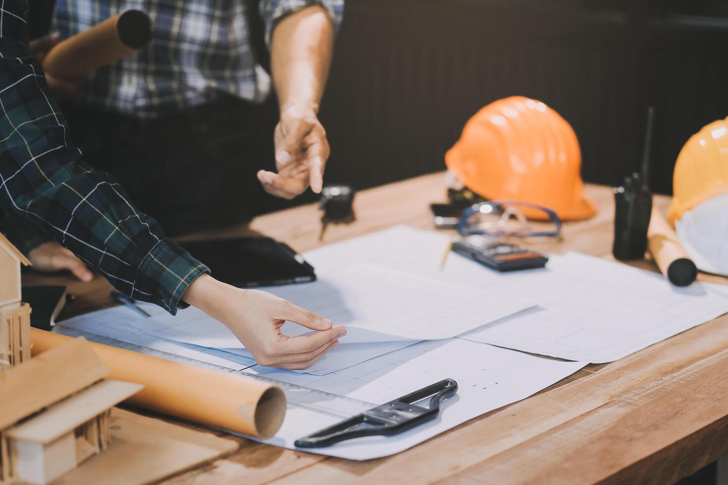 Asian young female architect discussing with japanese male building manager contractor for quality control site inspection and at house construction site in room under renovation project. photo