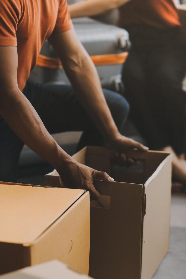 Asian couple, husband and attractive wife are happiness and are helping each other lose things into boxes, To prepare to move to a new home, concept to family and relocation photo