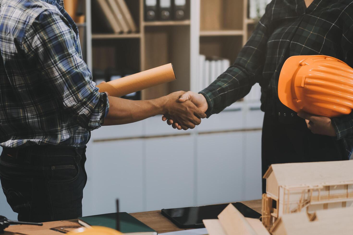 Architect and construction engineer holding hands while working for teamwork and cooperation concept after completing an agreement at construction site, office, close-up image photo