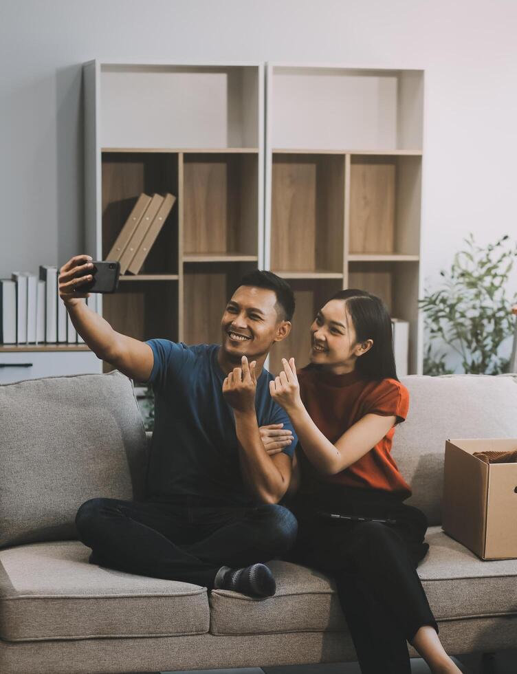 Happy excited, smiling asian young couple love using tablet pc, great deal or business success, received or getting cash back, tax refund, good news by mail while sitting on floor at home. photo