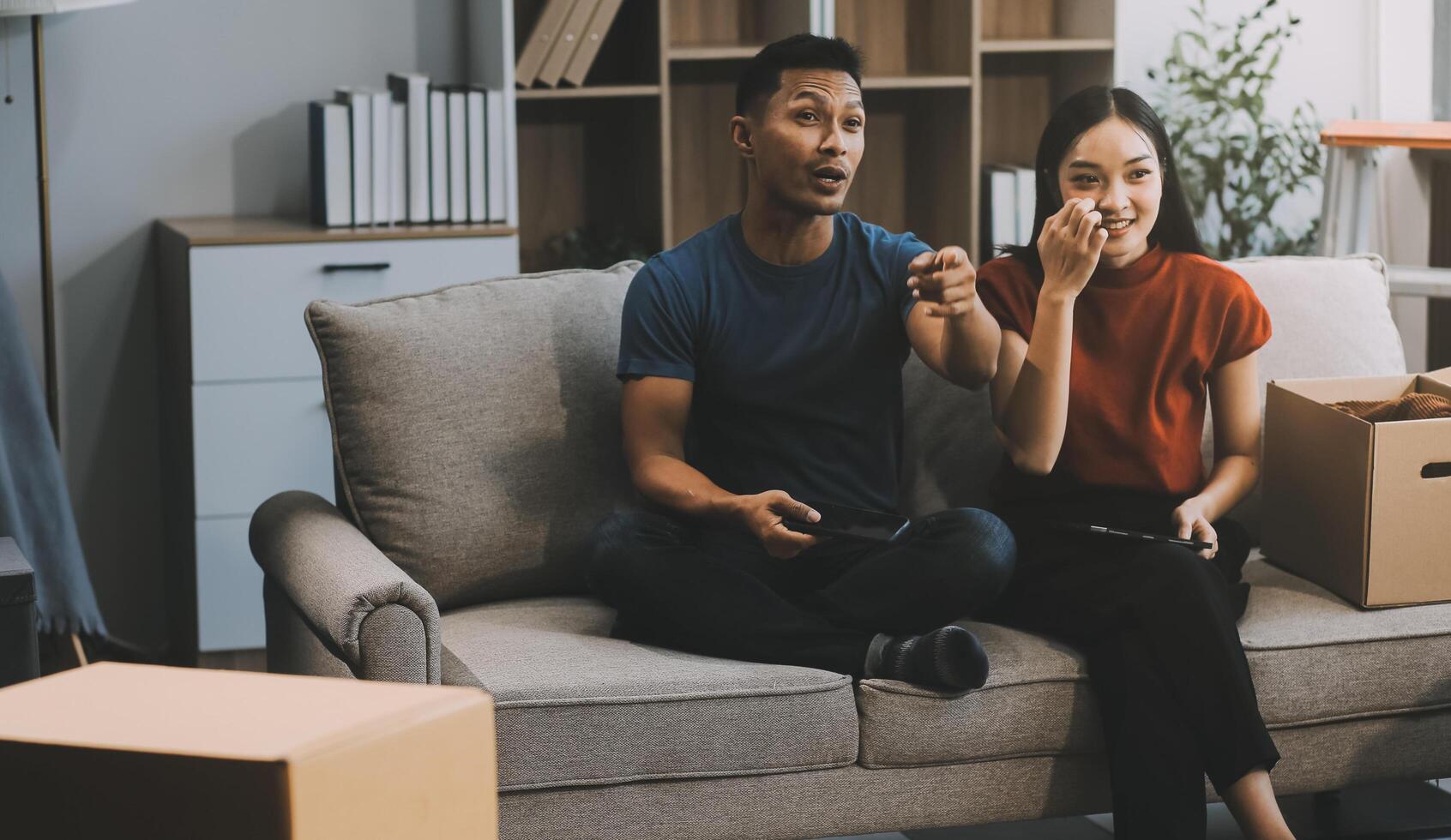 Happy excited, smiling asian young couple love using tablet pc, great deal or business success, received or getting cash back, tax refund, good news by mail while sitting on floor at home. photo