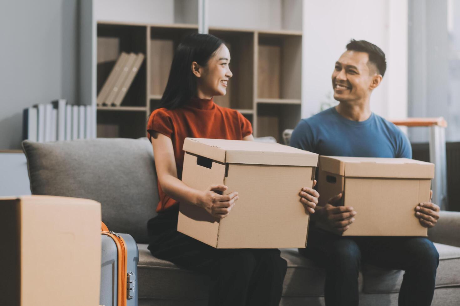 joven Pareja con grande cajas Moviente dentro un nuevo casa, nuevo Departamento para pareja, joven hombre y mujer Ayudar a levantar cajas y organizar cosas para el nuevo hogar, Moviente casa. foto