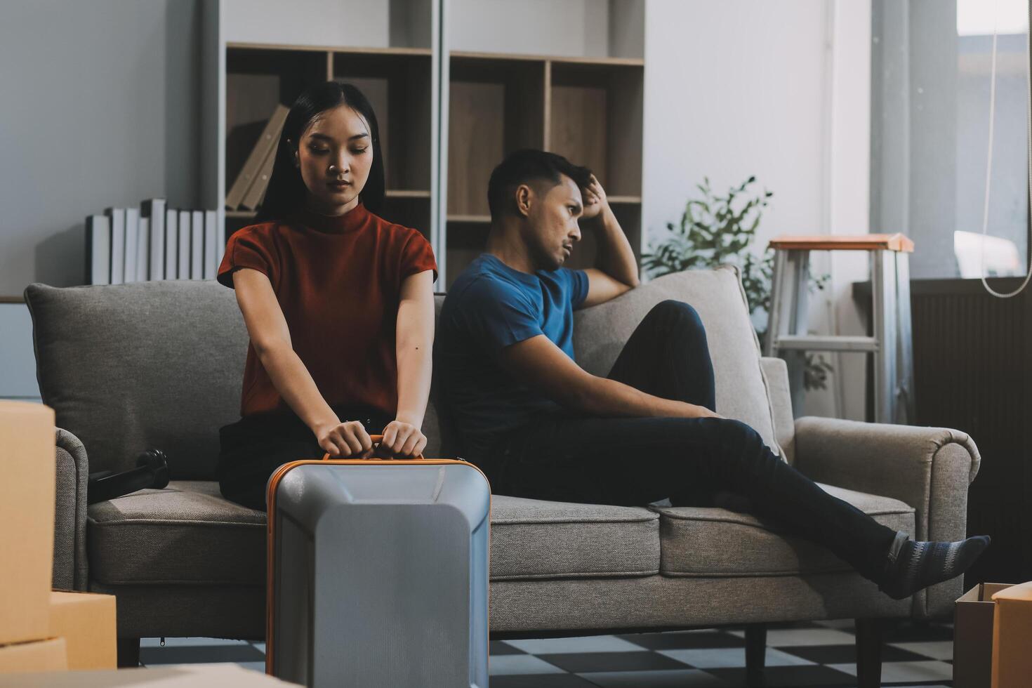 Family couple ignoring each other after a quarrel. Two people turn away and don't talk to each other. Angry young man and woman sitting back to back, with arms crossed on the sofa in the living room photo