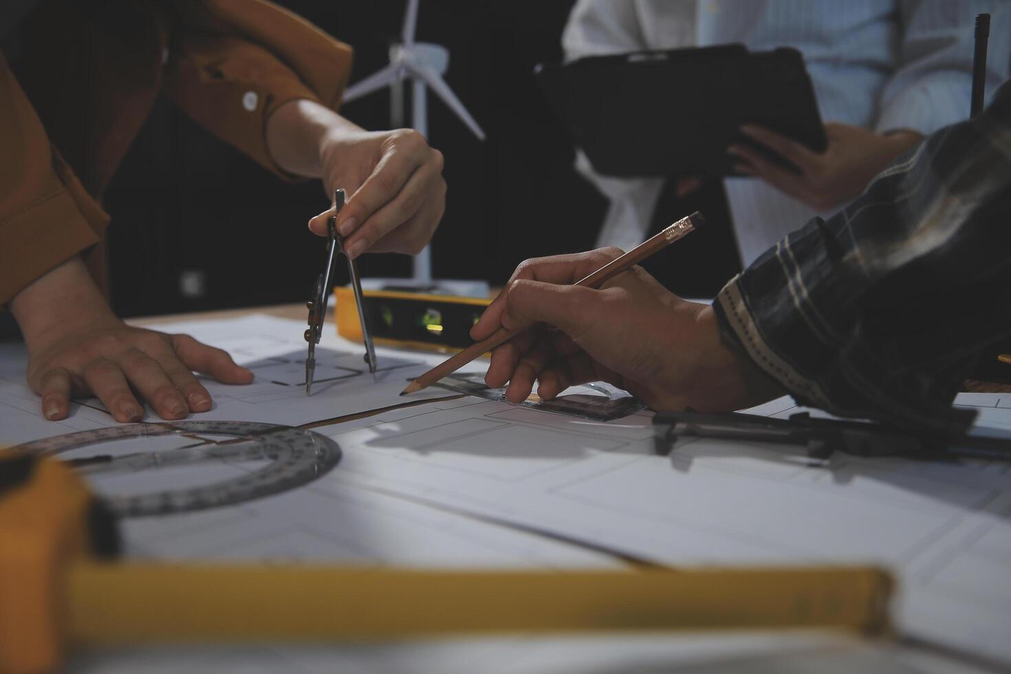 Team of multiethnic architects working on construction plans in meeting room. Engineers discussing on project in office. Mature businessman and woman standing around table working on blueprint. photo