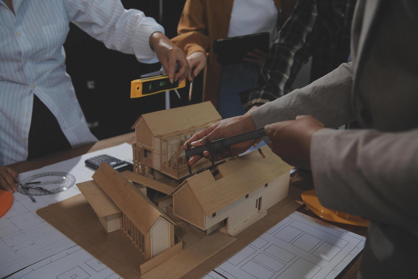 Team of multiethnic architects working on construction plans in meeting room. Engineers discussing on project in office. Mature businessman and woman standing around table working on blueprint. photo