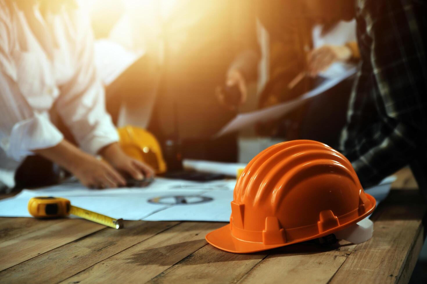 Team of multiethnic architects working on construction plans in meeting room. Engineers discussing on project in office. Mature businessman and woman standing around table working on blueprint. photo