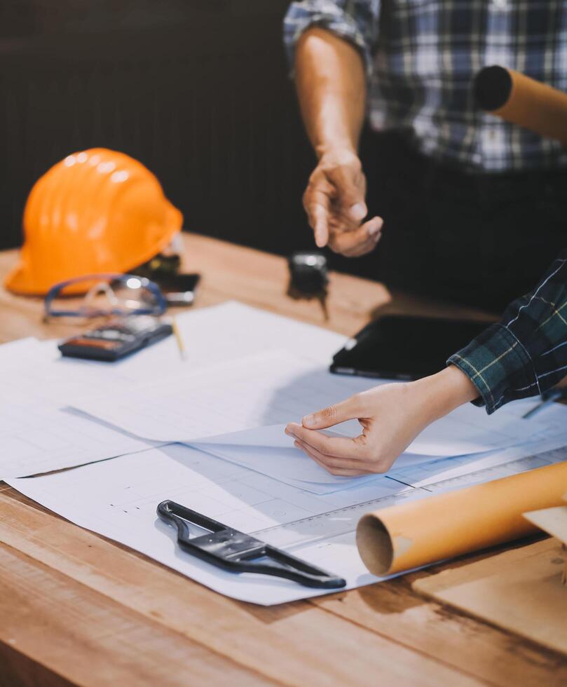 Asian young female architect discussing with japanese male building manager contractor for quality control site inspection and at house construction site in room under renovation project. photo