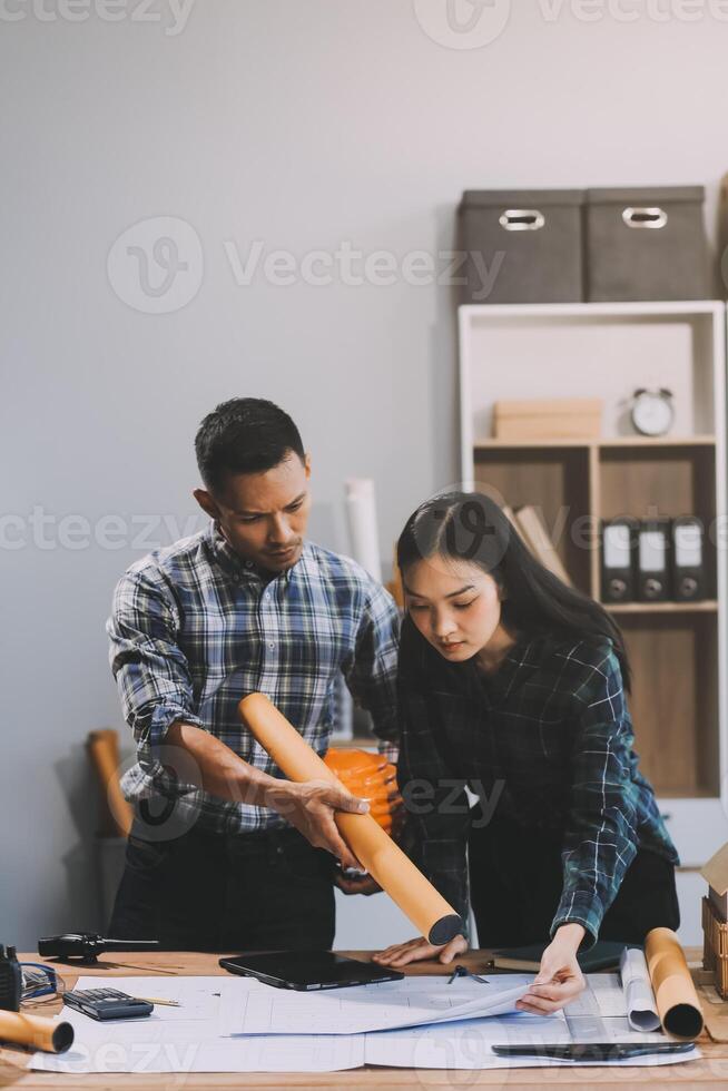 Asian young female architect discussing with japanese male building manager contractor for quality control site inspection and at house construction site in room under renovation project. photo