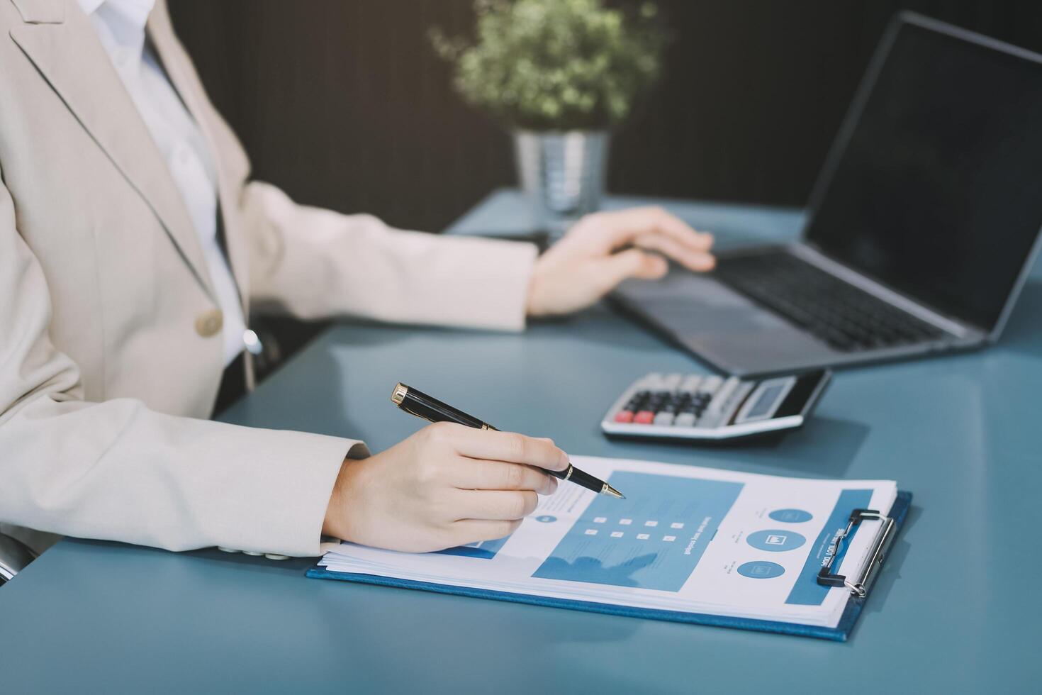 Asian Businesswoman Using laptop computer and working at office with calculator document on desk, doing planning analyzing the financial report, business plan investment, finance analysis concept. photo