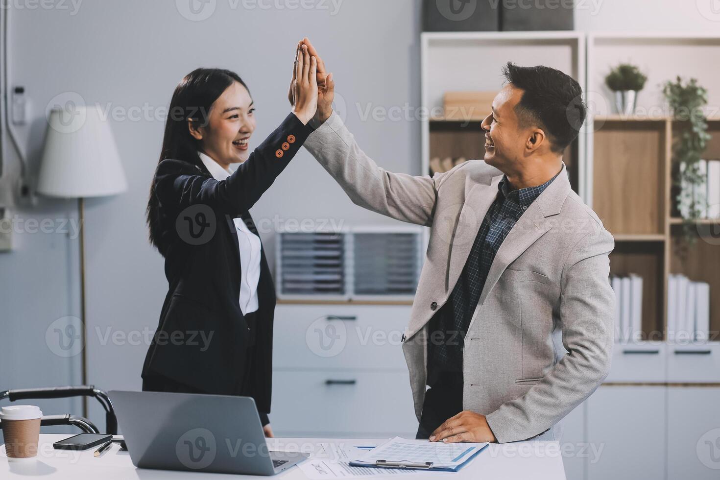 Two happy friendly diverse professionals, teacher and student giving high five standing in office celebrating success, good cooperation result, partnership teamwork and team motivation in office work. photo