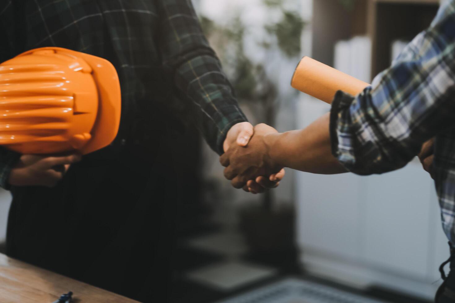 Architect and construction engineer holding hands while working for teamwork and cooperation concept after completing an agreement at construction site, office, close-up image photo