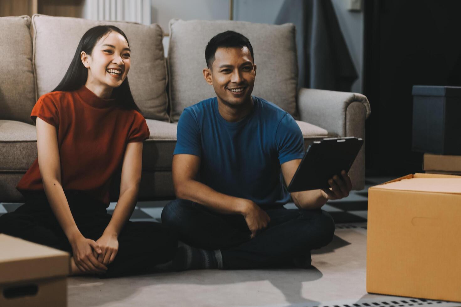 Happy excited, smiling asian young couple love using tablet pc, great deal or business success, received or getting cash back, tax refund, good news by mail while sitting on floor at home. photo