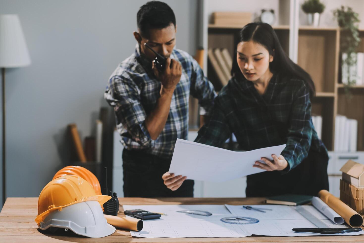 Asian young female architect discussing with japanese male building manager contractor for quality control site inspection and at house construction site in room under renovation project. photo